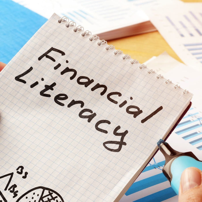 Close up of hands holding up a notebook with the words "Financial Literacy" written on it.